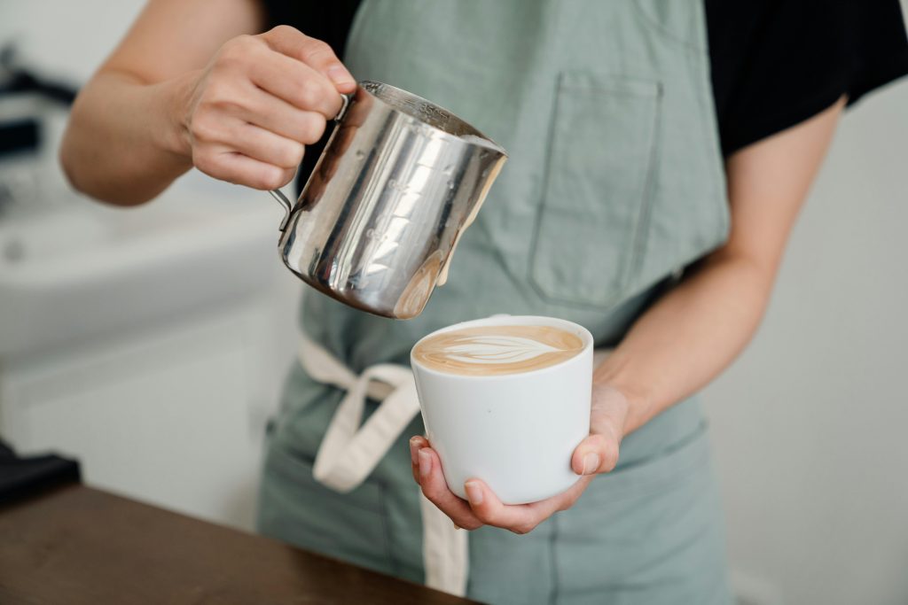 barista pouring milk into a fresh coffee latte